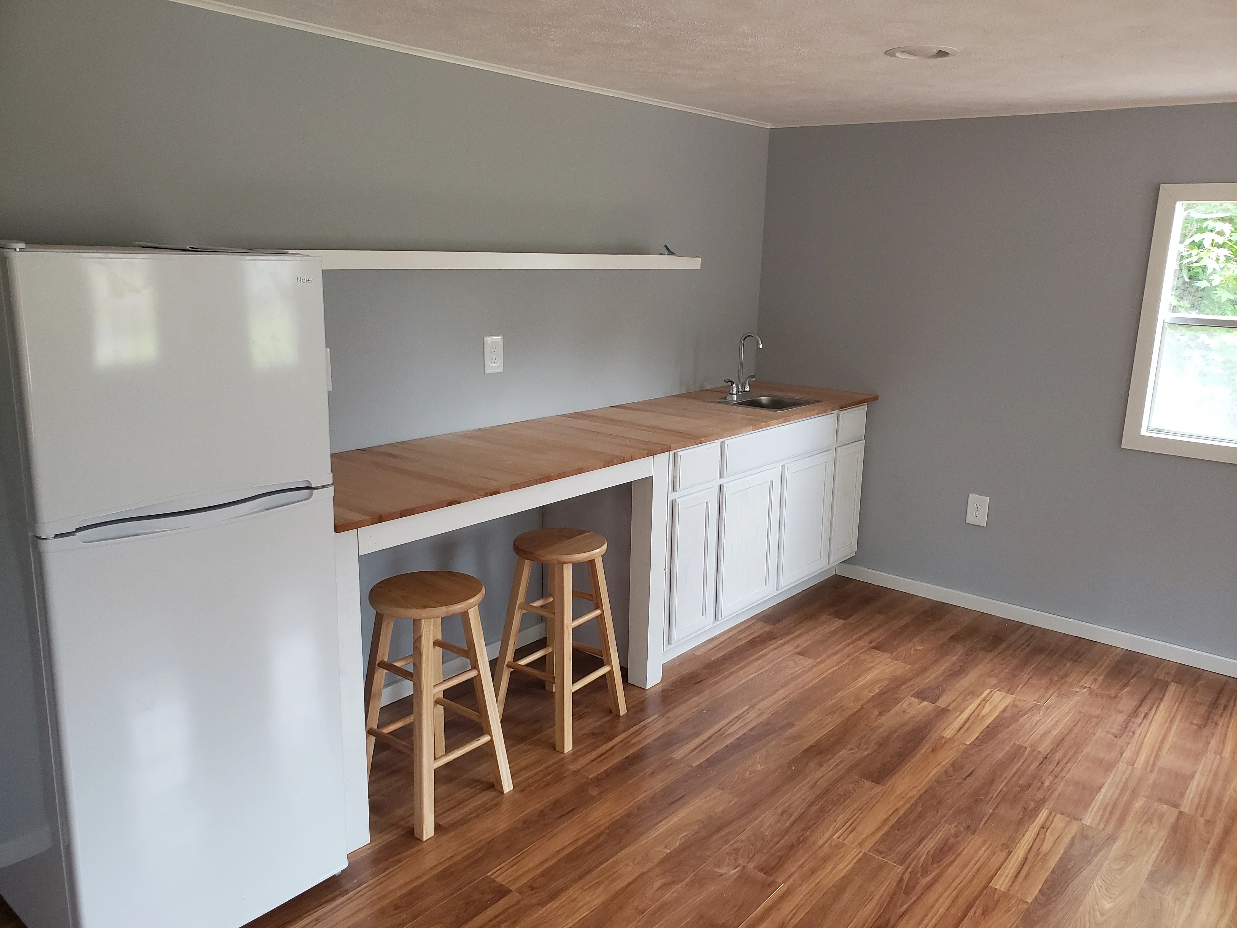 White cabinetry kitchen with wood countertop island, wood flooring, and gray painted walls