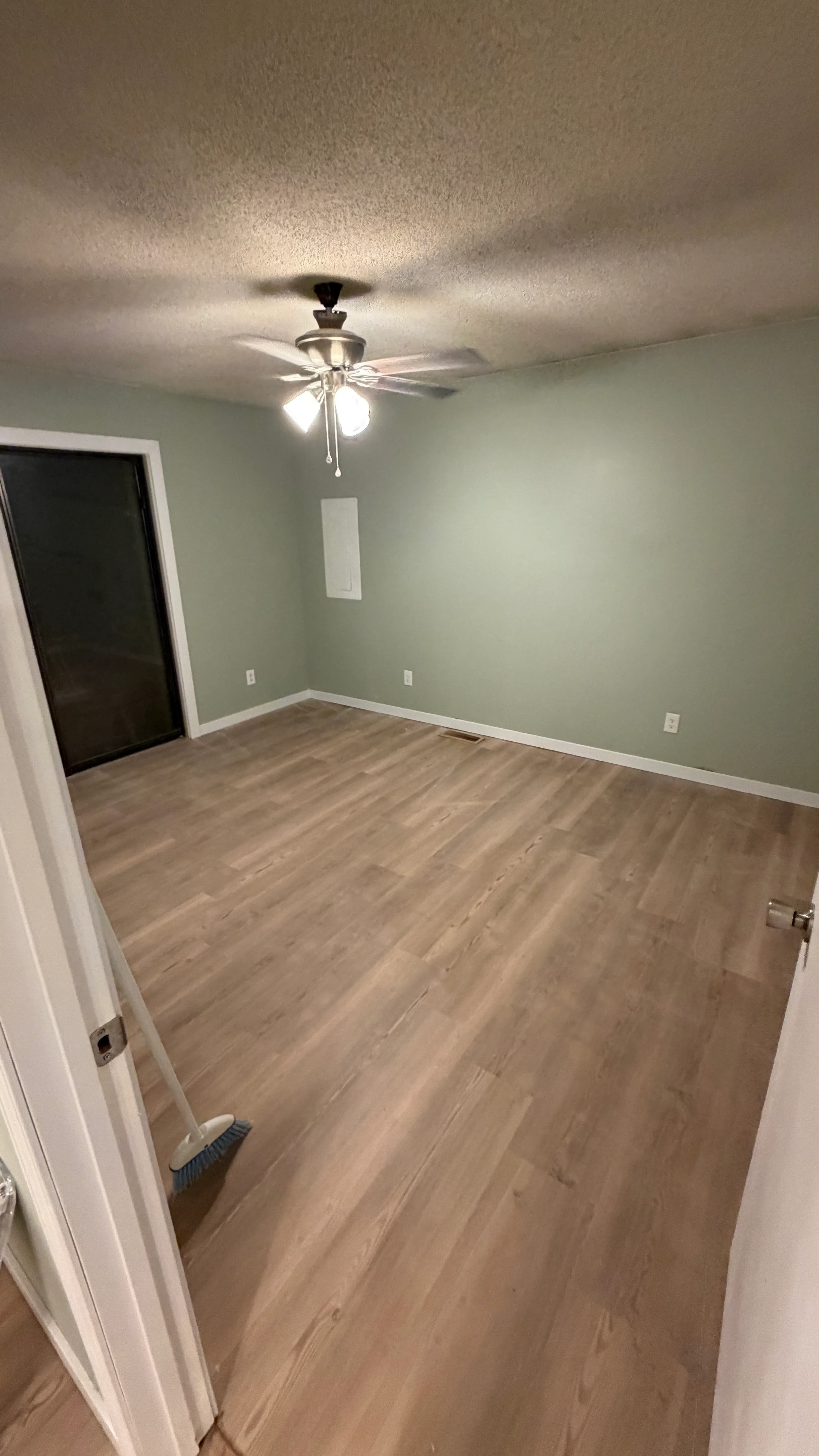 Bedroom with vinyl plank flooring, sage green walls, white trim, and ceiling fan with light fixture