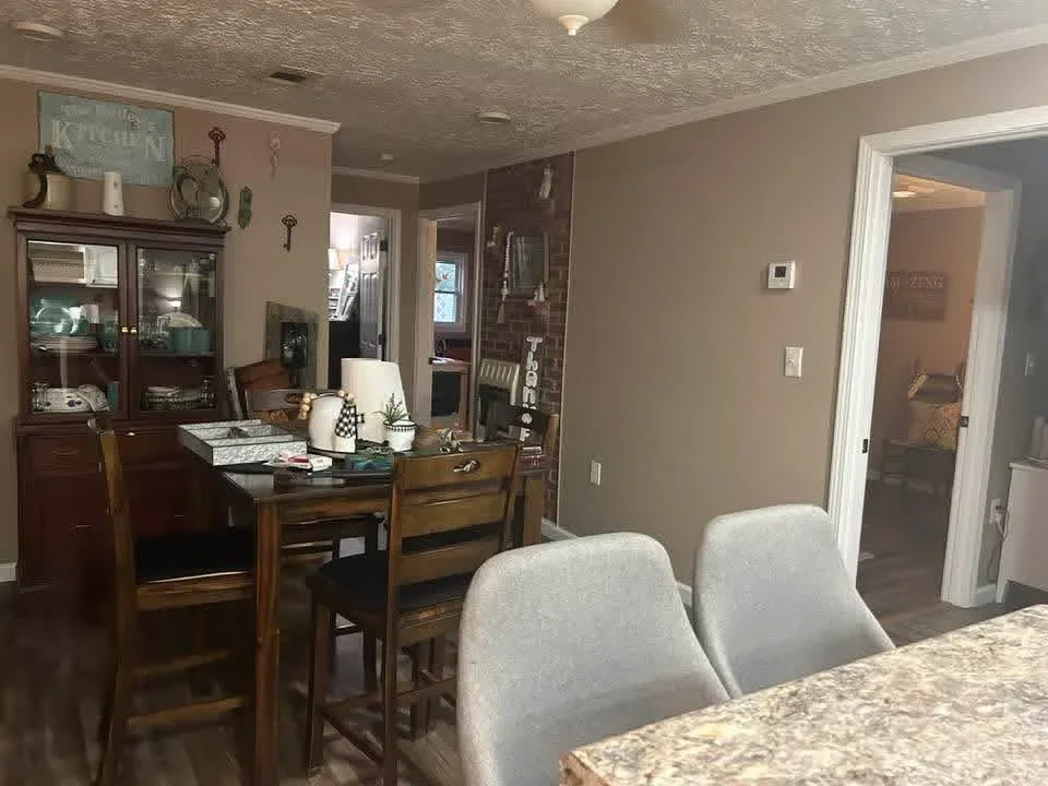 Open concept living and dining area with textured ceiling, neutral paint, white trim, and updated electrical work