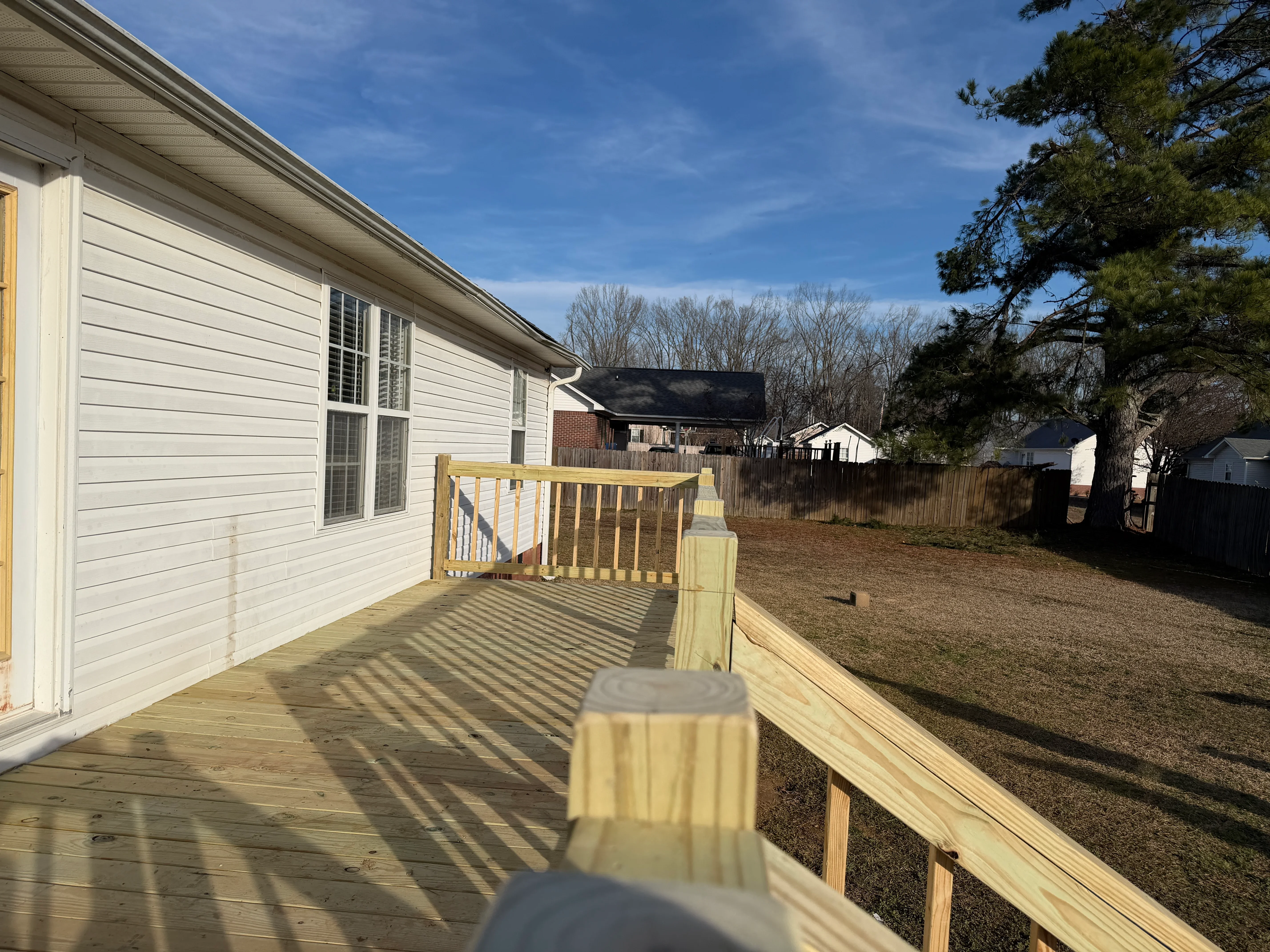 Newly constructed pressure-treated wood deck with railings attached to mobile home exterior