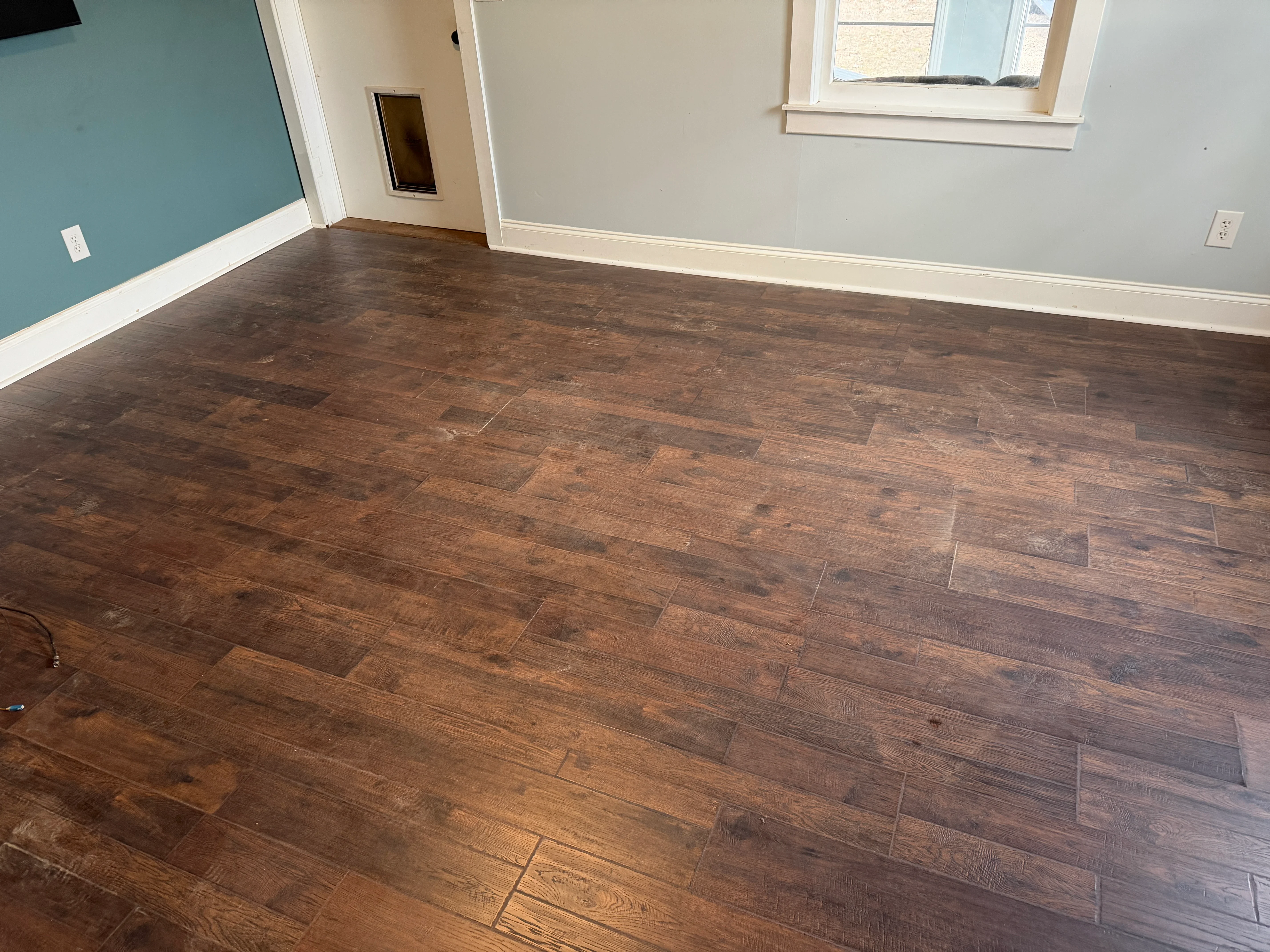 Dark wood-look vinyl plank flooring installed in room with white trim and painted walls