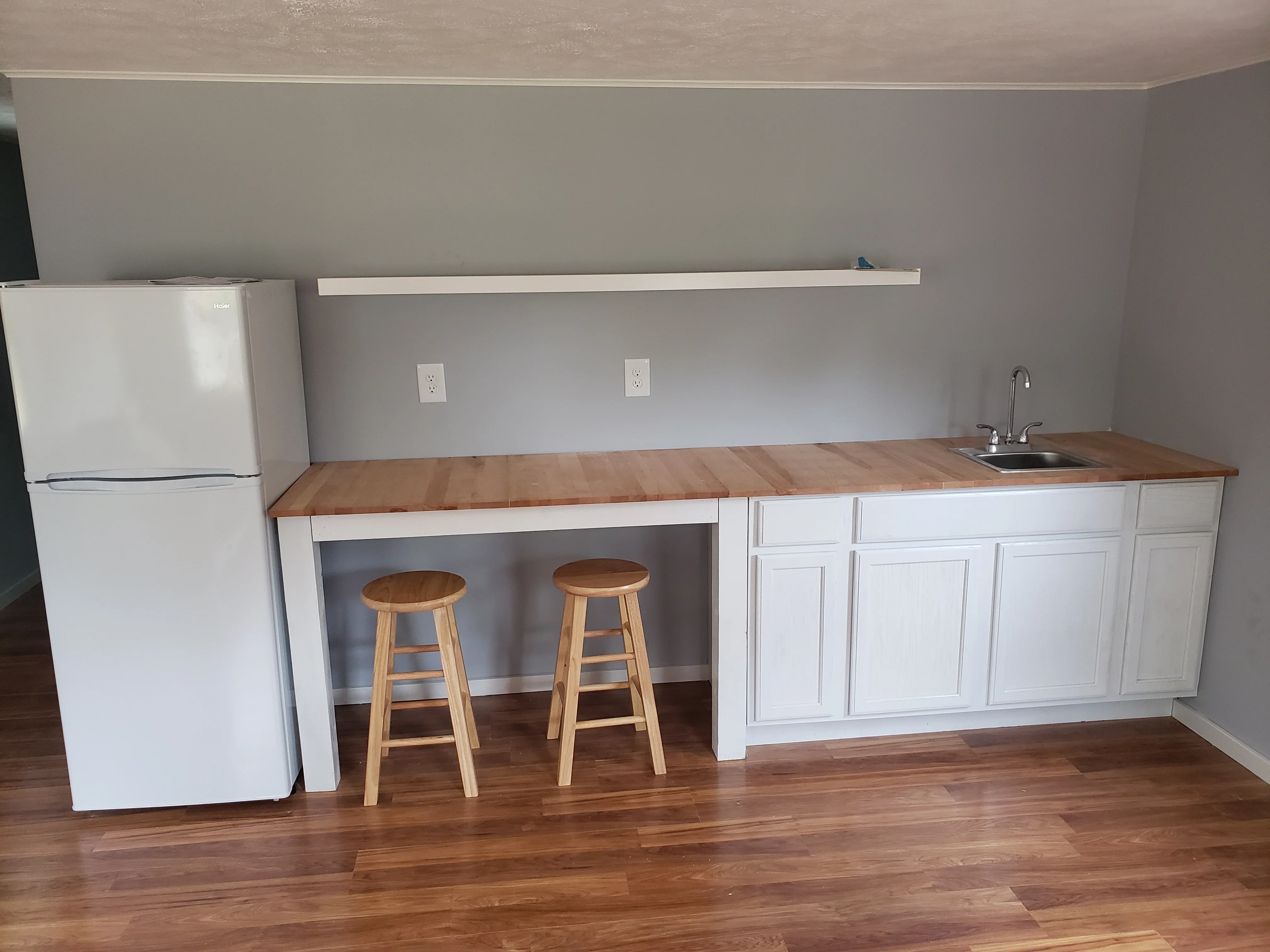 White cabinetry with wood countertop, bar seating, hardwood floors, and stainless steel sink
