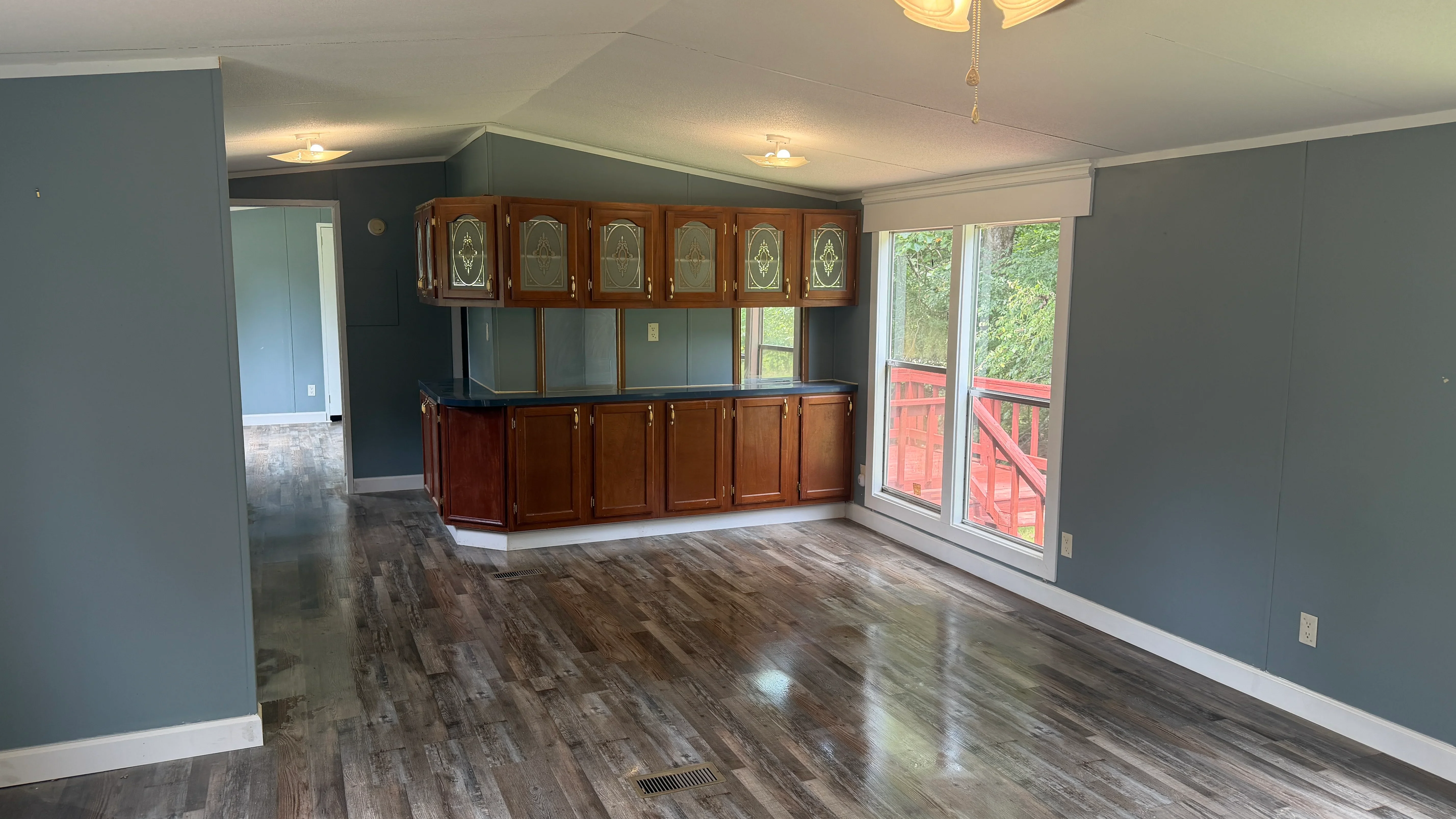 Open concept room with wood cabinetry, laminate flooring, and blue-gray painted walls