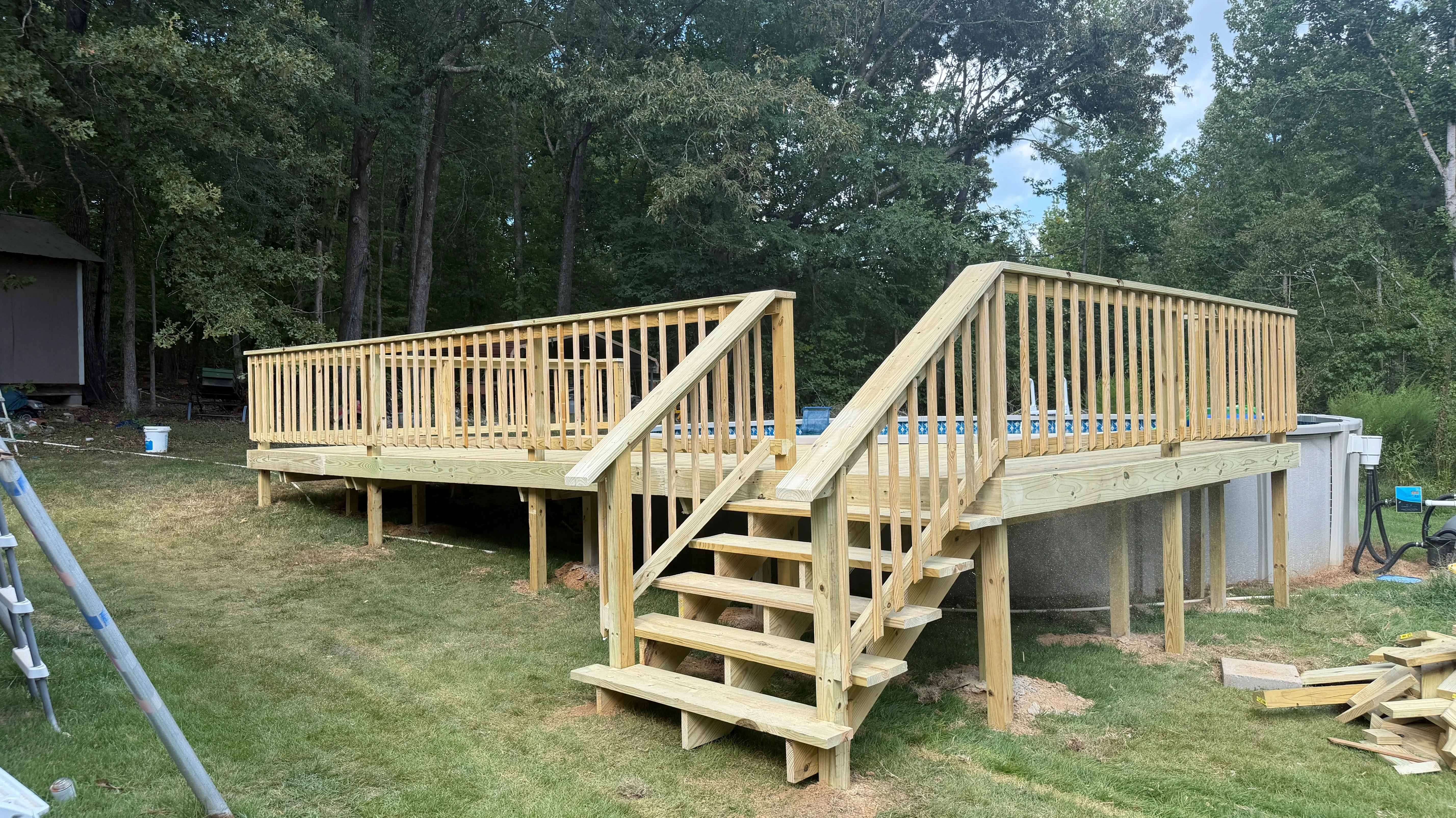 Newly constructed elevated wooden deck with dual staircases and vertical spindle railings