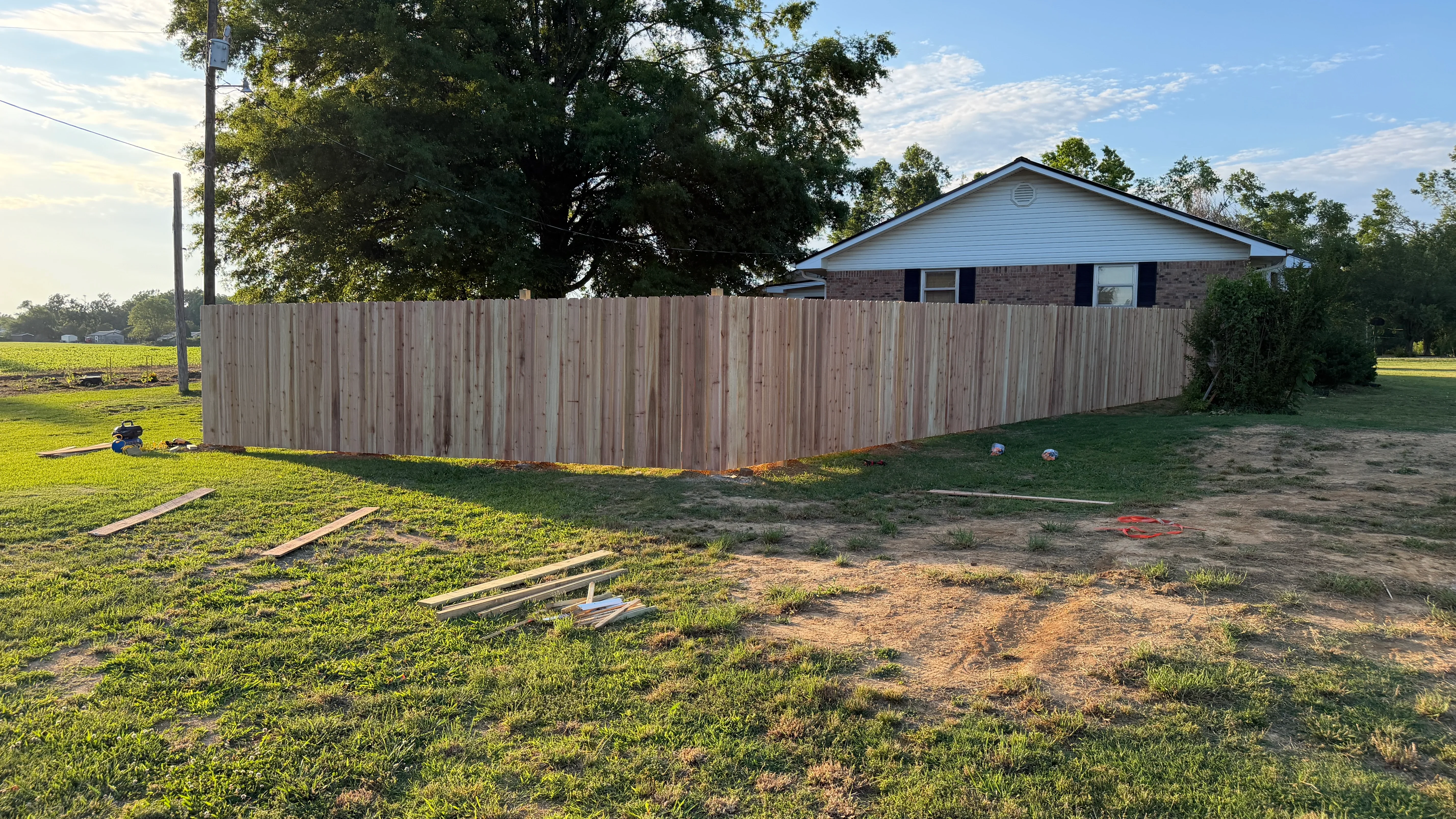 Tall wooden privacy fence with vertical boards installed around residential property perimeter