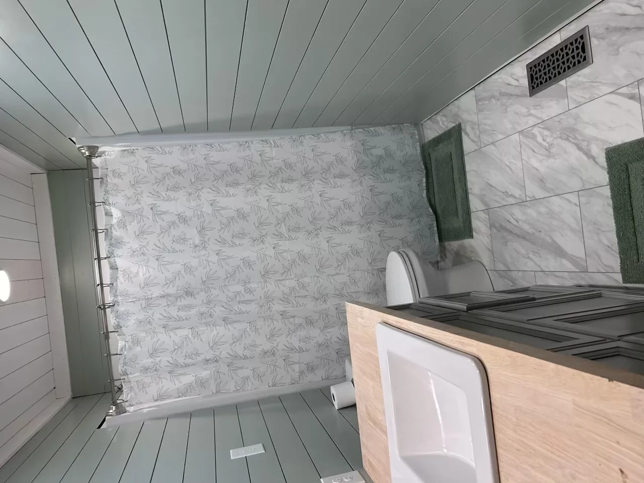 Bathroom with marble tile shower surround, wood vanity, and linear ceiling details
