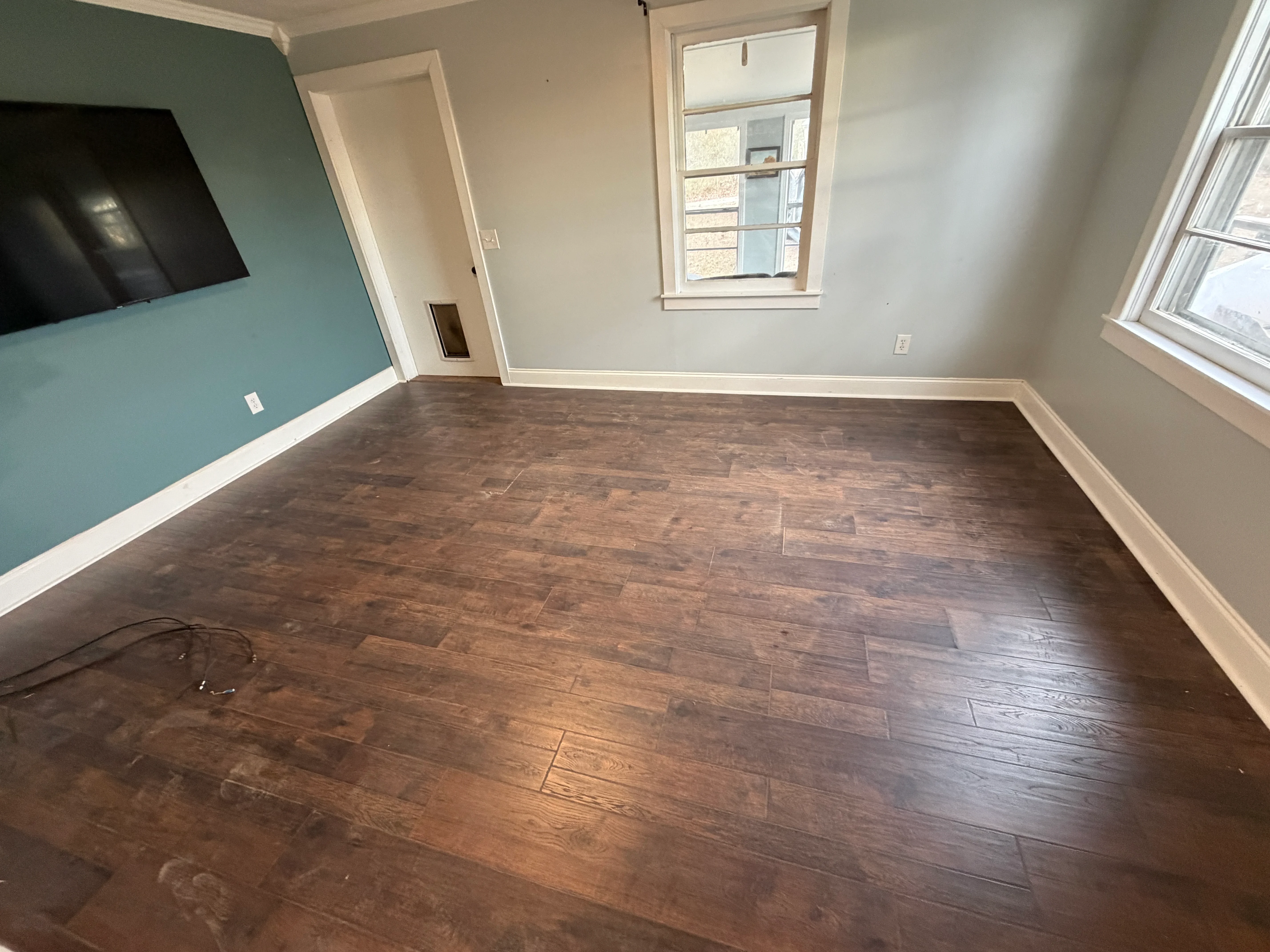 Hardwood floor installation with painted accent wall and white trim in residential room