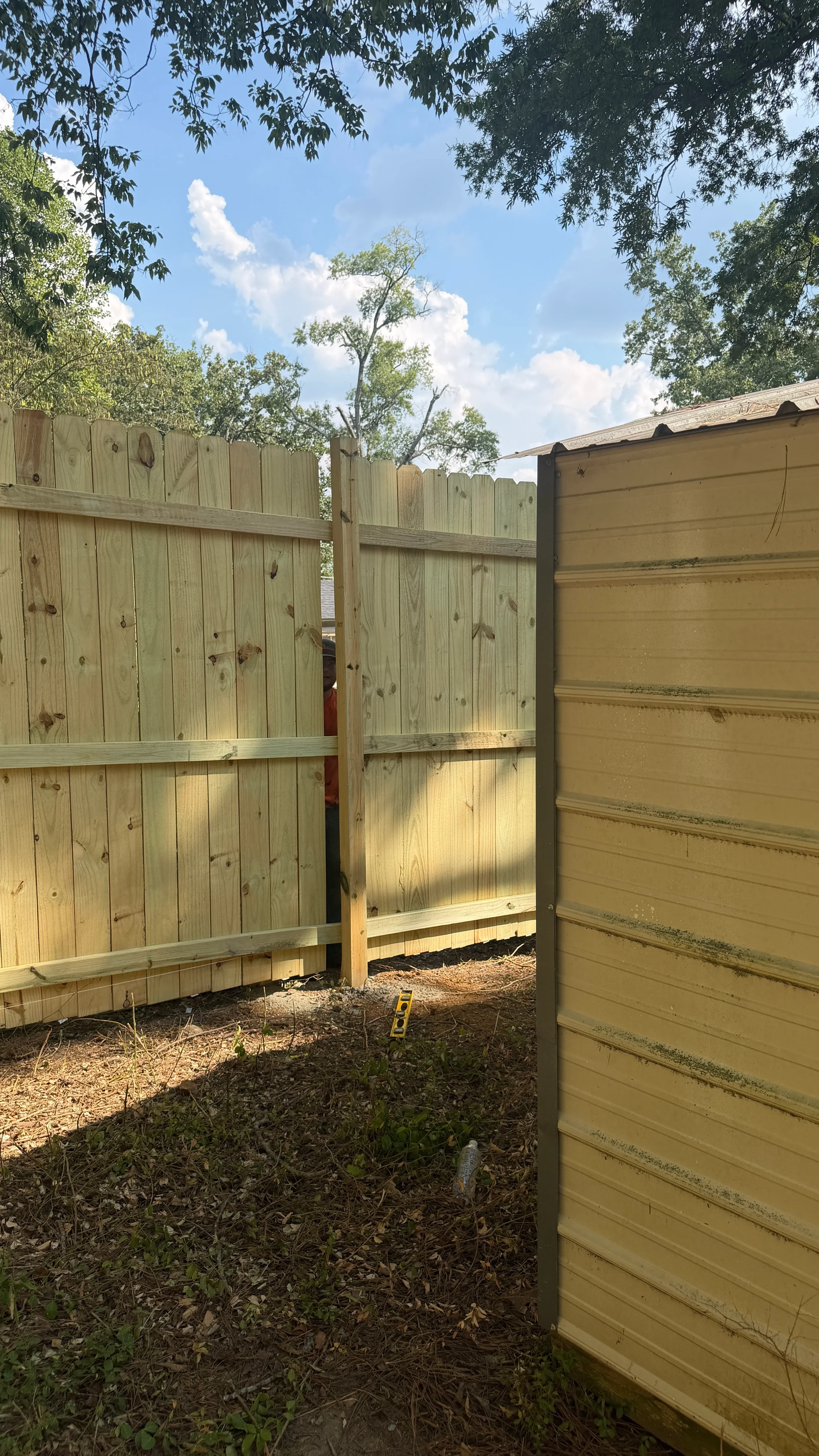 Newly installed wood privacy fence with vertical boards, horizontal rails, and gated entrance